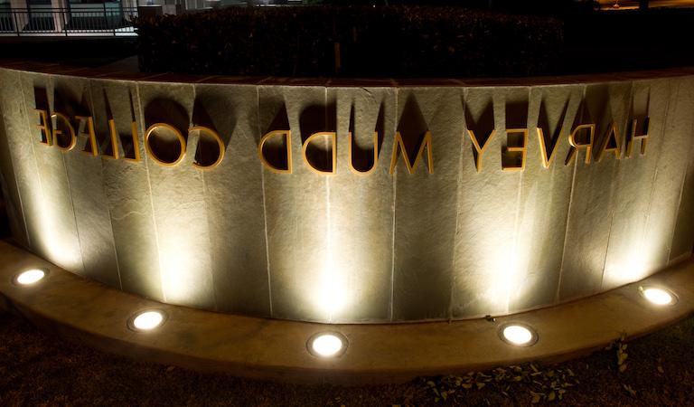 Stone sign lit up saying Harvey Mudd College